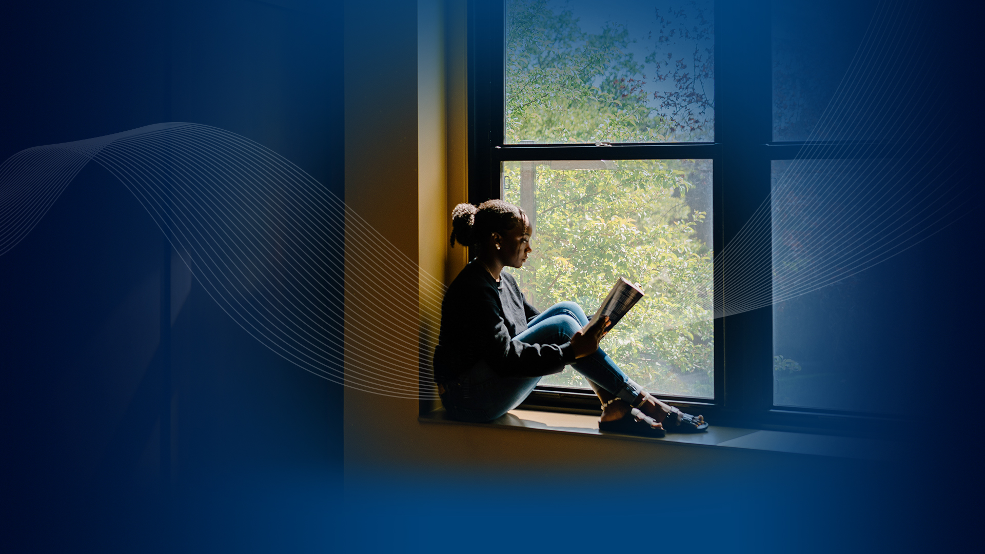 Student sitting in window, reading. 