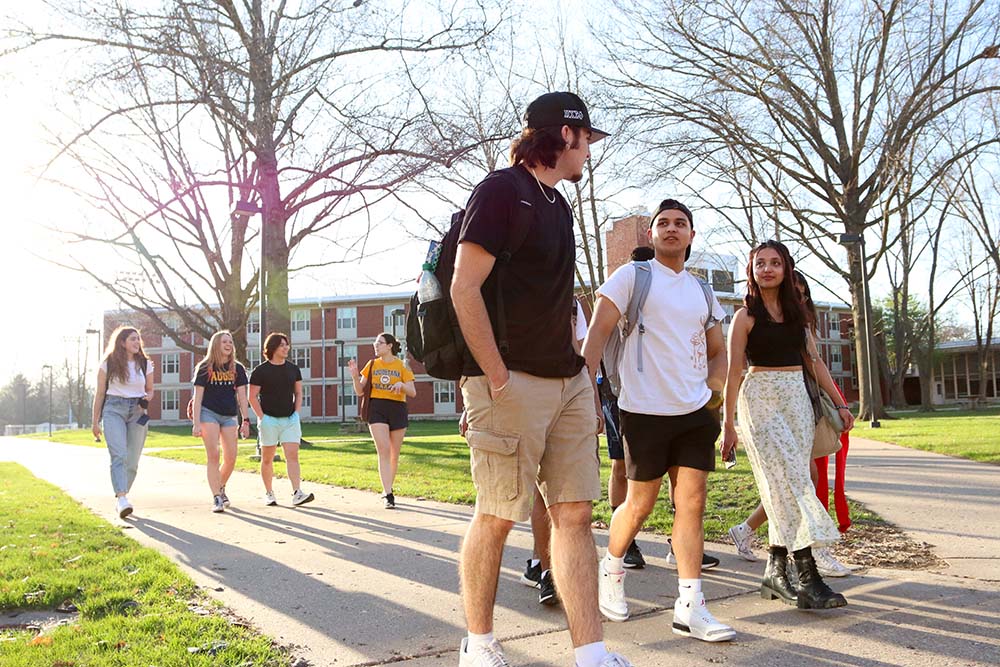 A group of students walking outside on a sidewalk on campus.