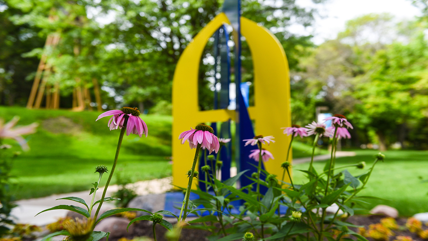 Photo of flowers blooming in front of a blue and gold A statue