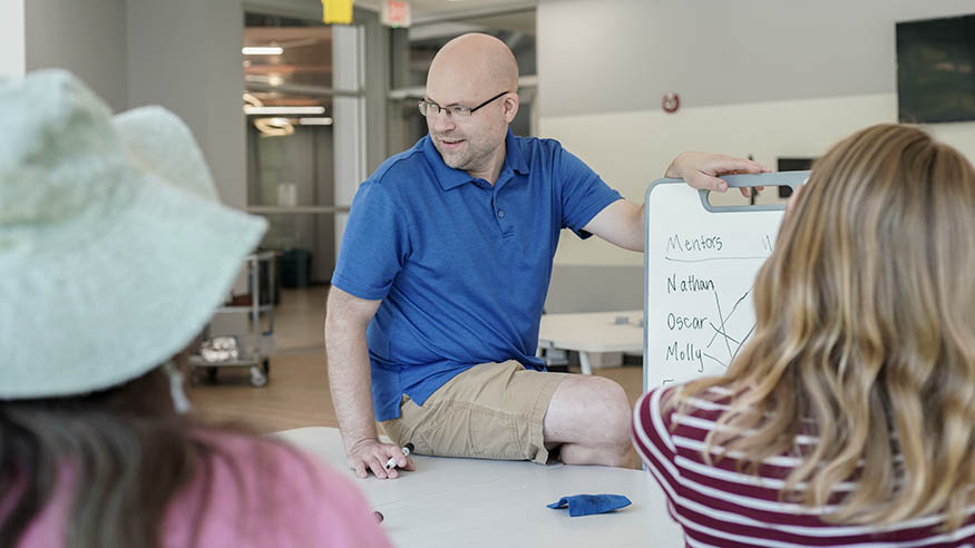 Dr. Nathan Frank presenting to students using a whiteboard