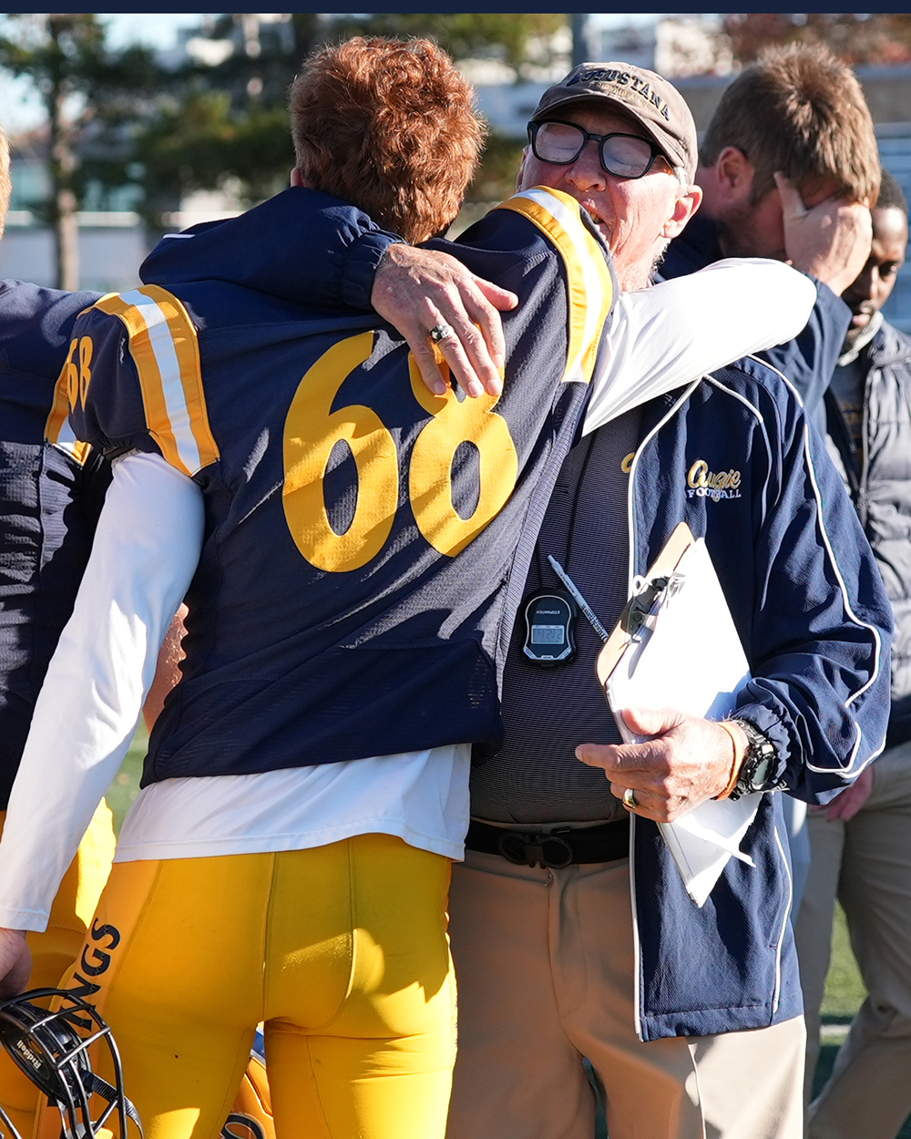 A coach hugging a football player on the sidelines