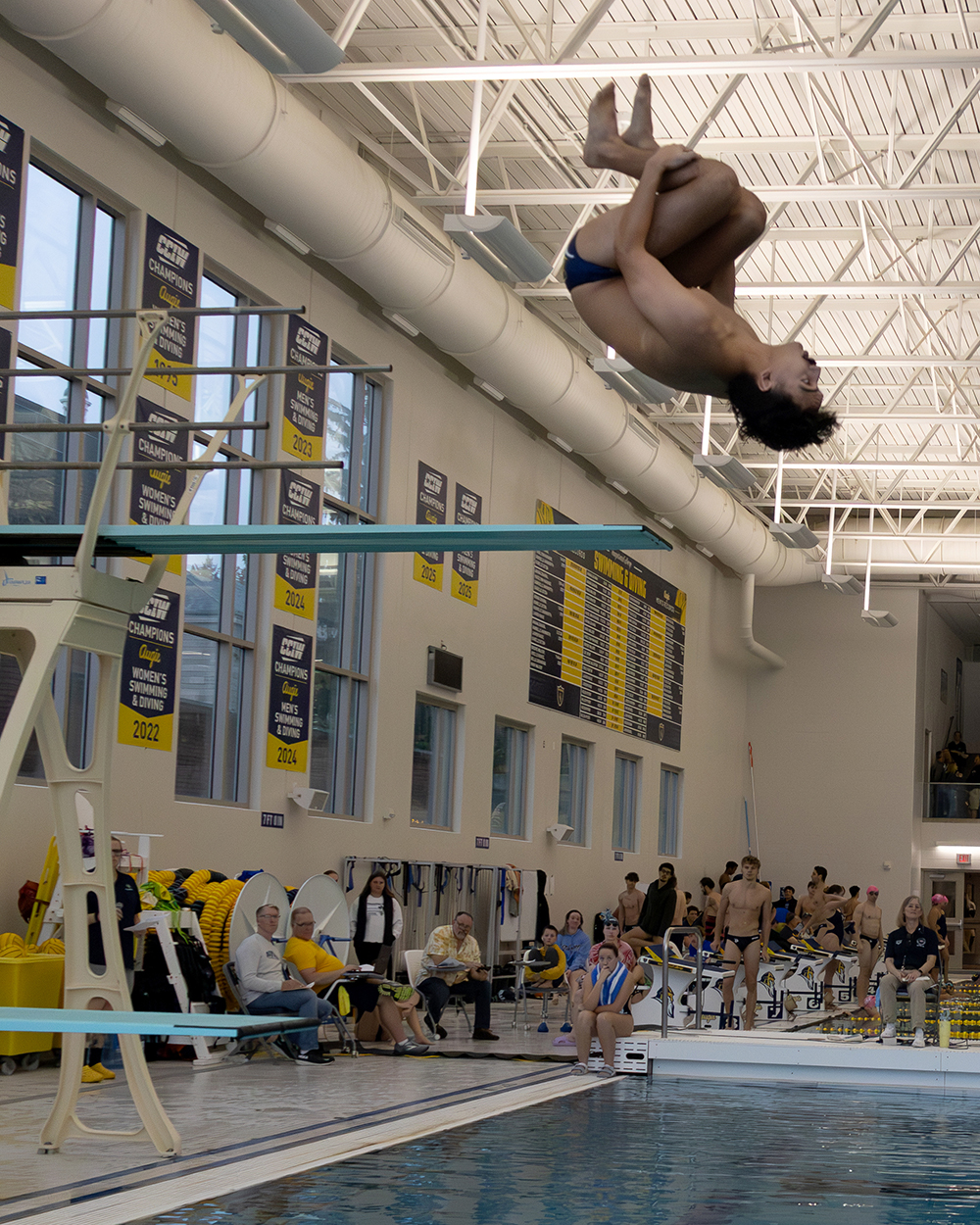 A student-athlete high-diving upside-down into the pool