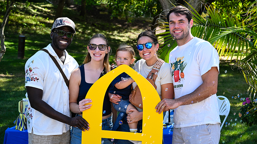 Friends holding a yellow "A" at Homecoming