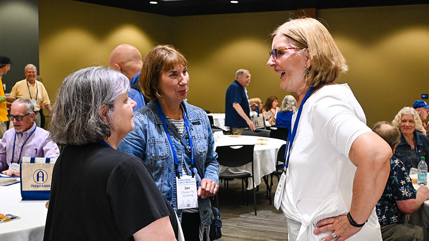 Three alumni chat at an event
