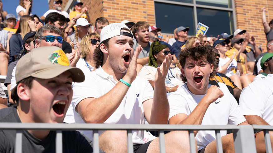 Fans shout in the stands at the Homecoming football game
