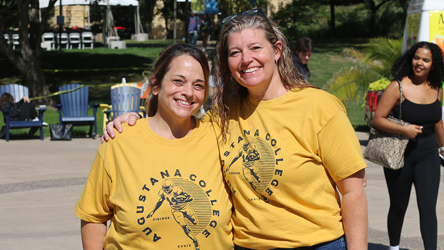 Two friends pose on the Quad wearing yellow Augustana Football T-shirts