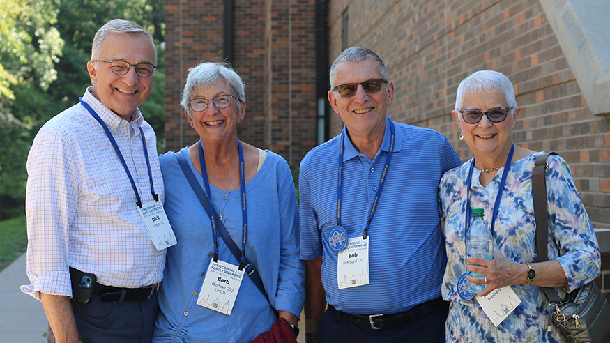 Four alumni pose outside of the Thomas Tredway Library