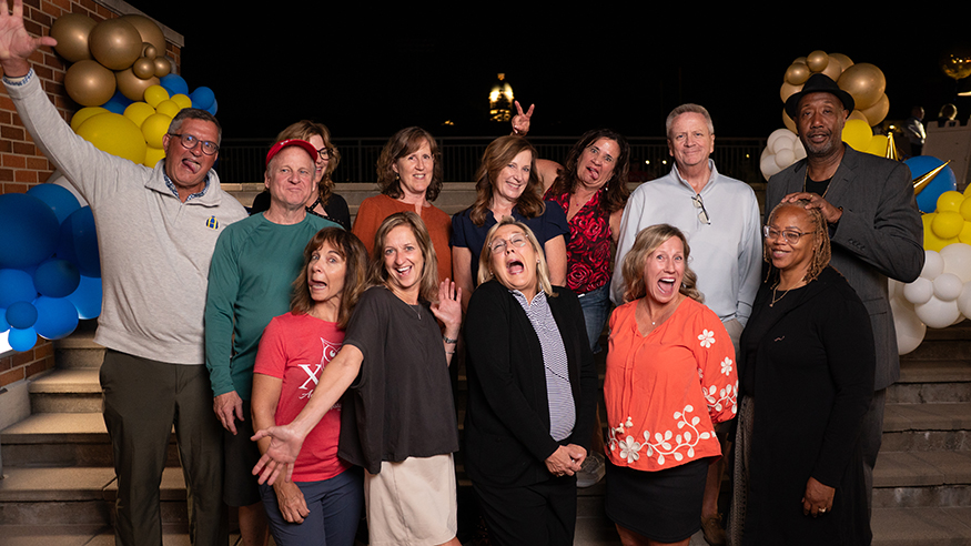 Several alumni pose with silly faces at an outdoor event