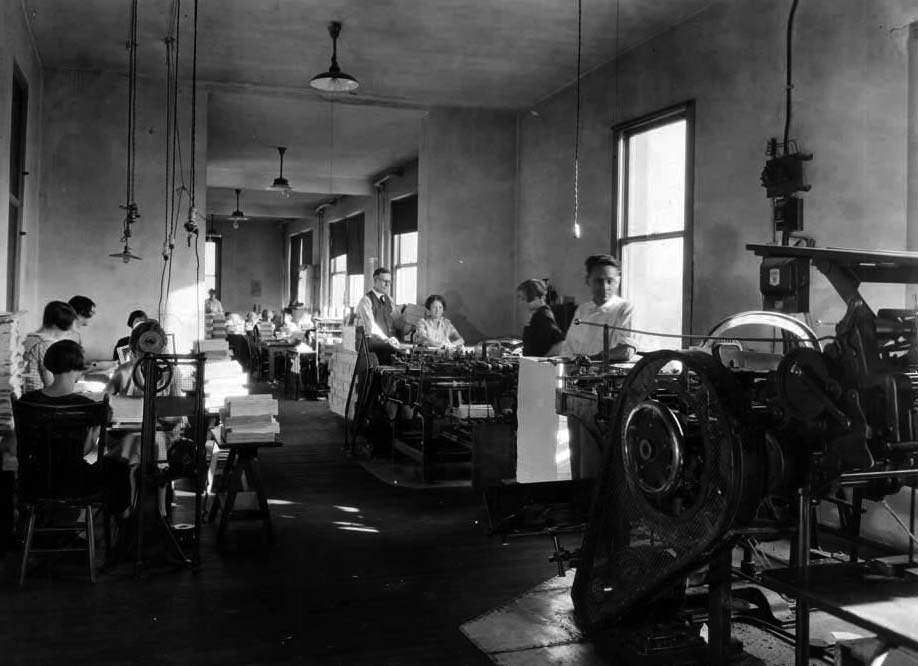 men and women at work in the book binding room of the 1920s 