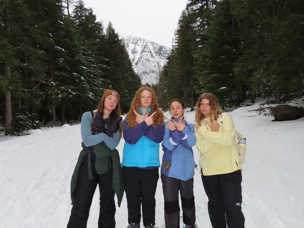 Four student posing in the snow with a mountain behind them