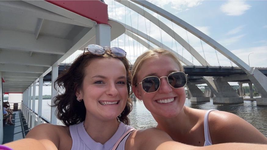 Jenny and a friend smiling on the Celebration Belle with the I74 bridge behind them.