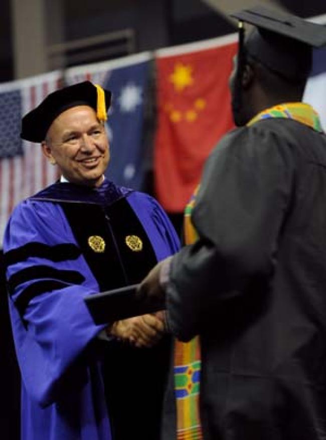 President Steve Bahls congratulates graduate Kofi Sam.