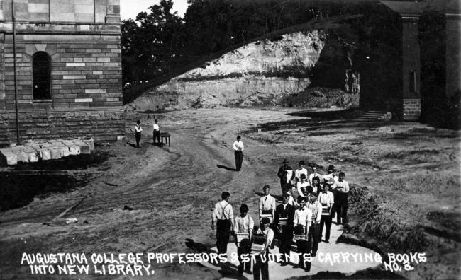 Augustana College professors and students carrying books from Old Main to the new Denkmann Library in 1910.