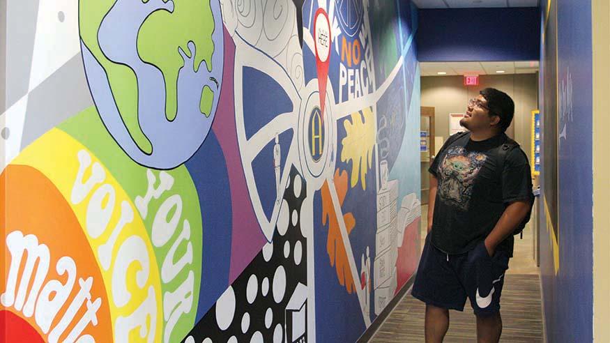 Sophomore Jesus Murillo in front of the You Belong Here Lounge mural