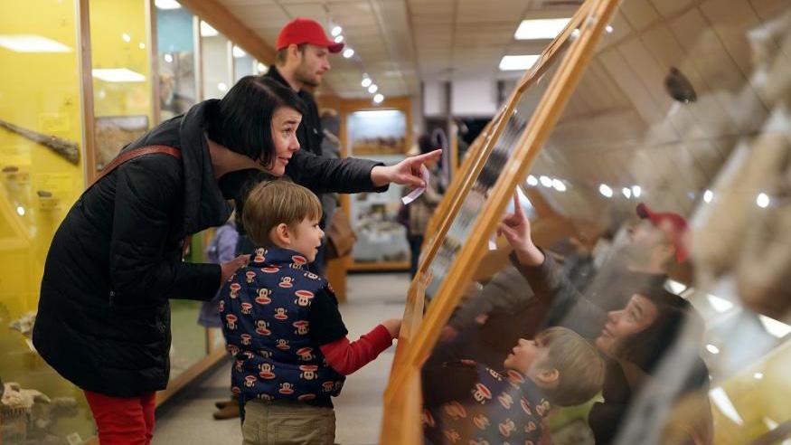 A man, woman and child in front of a display case