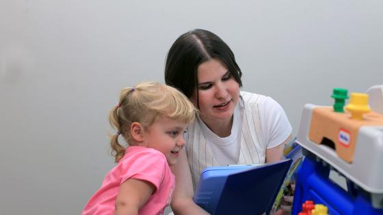 A student reading a book to a young child